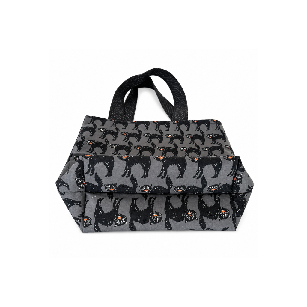 A gray fabric tote bag with black handles, featuring an all-over repeating pattern of black dogs with orange eyes on a white background.